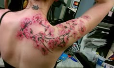 a woman with pink flowers on her back and arm tattooing it's chest