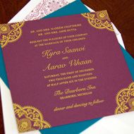 the wedding card is on top of two envelopes, one in purple and gold