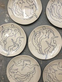 six plates with drawings on them sitting on a counter top in front of a wall