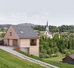 a small house on the side of a hill with a church in the back ground