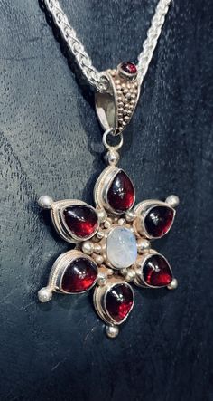 Stunningly beautiful Garnet with a lovely irresistible moonstone in the center! Handmade, fair trade sterling silver. 2” L