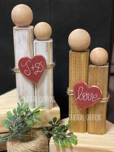 three wooden pegs with hearts and love written on them