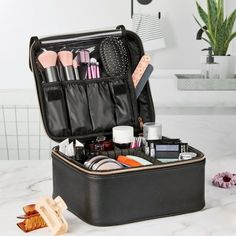 an open suitcase on a table with makeup and other items in it next to a potted plant