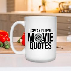 a white coffee mug that says i speak fluent movie quotes on it next to peppers