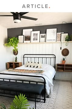 a bedroom with a bed, plant and pictures on the wall above it's headboard