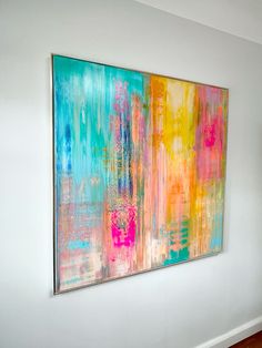 an abstract painting hangs on the wall above a bed