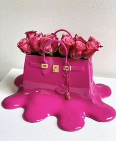 a pink purse with flowers in it sitting on top of a white table next to a wall