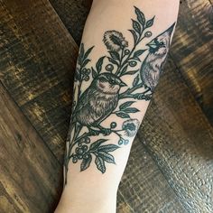 a woman's arm with a bird and flower tattoo on it