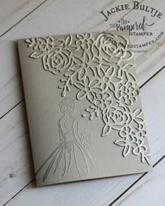 a wedding card with an intricate design on the front and back, sitting on a wooden table