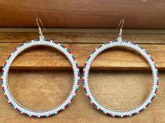 pair of beaded hoop earrings hanging from wooden board with wood plank in the background