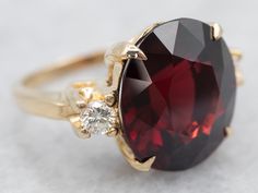 This ring features a simple and classically designed mounting, the structural openwork shoulders lend a sense of light and grace to the mounting. Cut into a classic oval cut, the deep red cherry garnet in the center adds a lovely pop of color and also an interesting shape to a simple ring! Twinkling diamonds on either side of the stone add an extra bit of sparkle.Metal: 14K Yellow GoldGem: Pyrope Garnet 10.14 CaratsGem Measurements: 12.5 x 13.7 mm, OvalAccents: 2 Diamonds totaling .20 Carats, G in Color, VVS in Clarity Ring Size: 4.25Marks: “14K” Stamped on the inside band Gold Garnet Ring, Pyrope Garnet, Garnet And Diamond Ring, Ring Three Stone, Right Hand Ring, Simple Ring, Right Hand Rings, Hand Ring, Garnet Jewelry