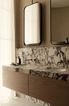 a bathroom with marble counter tops and two mirrors