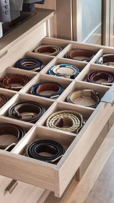 an open drawer with many belts in it