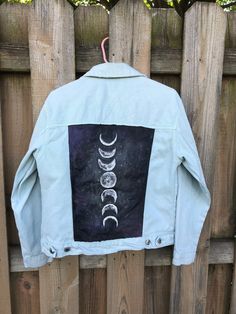 the back of a jacket with phases printed on it, hanging on a fence in front of a wooden fence