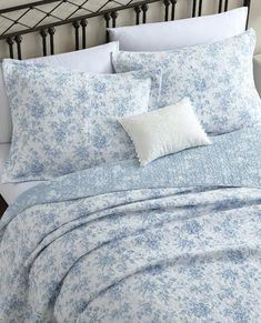 a bed with blue and white comforters on top of it