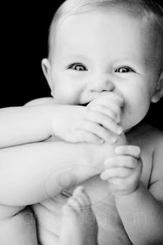 a black and white photo of a smiling baby