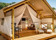 a tent is set up on a wooden deck with chairs and an awning over it