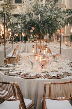 the table is set with white linens and gold place settings, greenery and candles