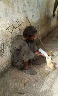 a man kneeling down next to a wall with a cat on it's side