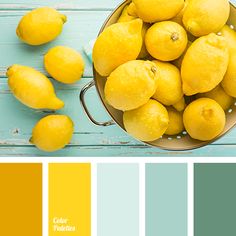 a pan filled with yellow lemons on top of a blue wooden table next to a bucket