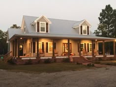 a house that is lit up with lights on the porch and covered in shingles