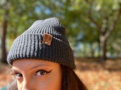 Give the gift of warmth and style! This knit beanie is perfect for hiking, camping, and perfect for keeping warm! Beanie is a dark charcoal gray color, and is made of a soft wool/acrylic blend. Attached is an engraved leather label tag with a brass rivet. The leather label is engraved on both sides, so whether you wear the hat with the brim up or down, the label will still show the design in the correct orientation. Choice of circle logo or trees available at checkout. Care - Hand wash, dry flat Warm Outdoor Hat One Size, Comfortable Beanie Hats For Fall, Adjustable Knitted Beanie For Outdoor, Comfortable Beanie For Fall, Outdoor Adjustable Knitted Beanie, Fall Beanie For Everyday Use, Outdoor Soft Knit Beanie Cap, Comfortable Warm Hats For Fall, Warm Everyday Hats For Fall