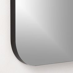 a mirror mounted to the side of a white wall next to a black framed object