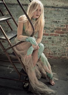 a woman sitting on top of a stair case next to a brick wall and ladder