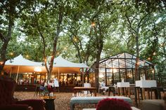 a tent set up with tables and chairs under trees