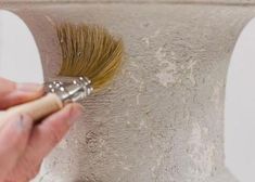 a person using a brush to paint a vase