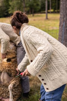 a woman is petting a dog outside in the grass while another person stands nearby