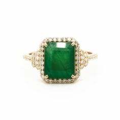 an emerald and diamond ring on a white background