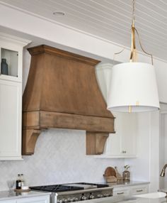 a kitchen with white cabinets and an island in front of a stove top oven that has a light hanging from the ceiling