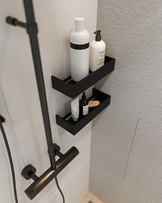 a bathroom with two shelves on the wall holding soap, lotion and shampoo