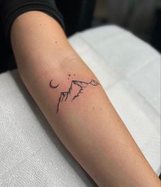 a woman's arm with a tattoo on it that has mountains in the background