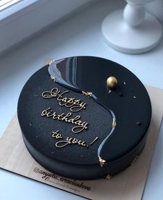 a black birthday cake with writing on it