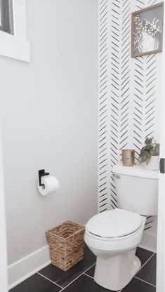 a white toilet sitting in a bathroom next to a wall with black and white lines on it