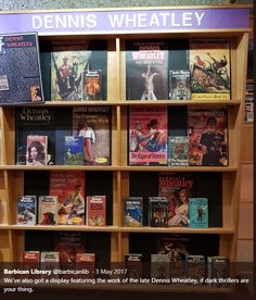 a book shelf filled with lots of books next to a sign that says dennis wheatley