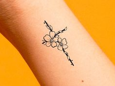 a small flower tattoo on the left arm is shown in black ink, and it has an arrow at the center