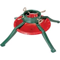 a green and red bird feeder with two birds on it's legs, sitting on top of a red plate