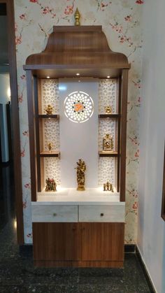 an ornate display case with many small items on it's shelves in front of a floral wallpapered wall