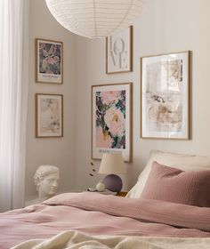 a bedroom with pink bedding and pictures on the wall