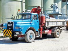 a large blue truck parked in front of a building next to other trucks and machinery