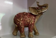 an elephant figurine is on display in a white room with red and gold decorations