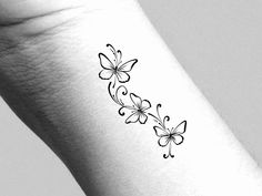 a black and white photo of a butterfly tattoo on the wrist, which is decorated with flowers