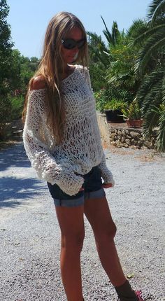 a woman is standing in the middle of a gravel road wearing short shorts and a white sweater