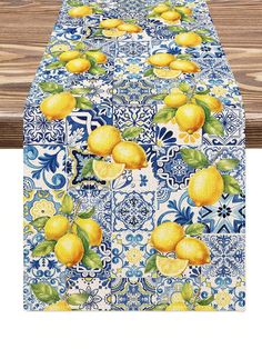 a blue and white table cloth with yellow lemons on it, sitting next to a wooden bench