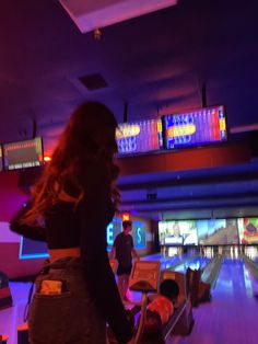 a woman standing next to a bowling alley