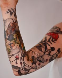 a woman's arm covered in tattoos with flowers and birds on the back of her arm