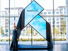 a man standing in front of a large sign with the words marathon oil on it